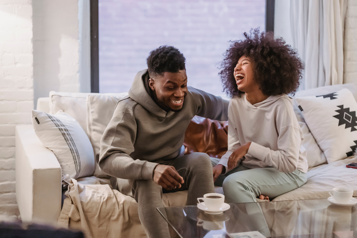 Expressive young black couple having fun at couch at home